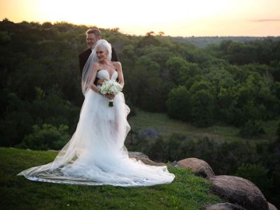 Blake Shelton is holding Gwen Stefani from behind as they are posing in their wedding dress.